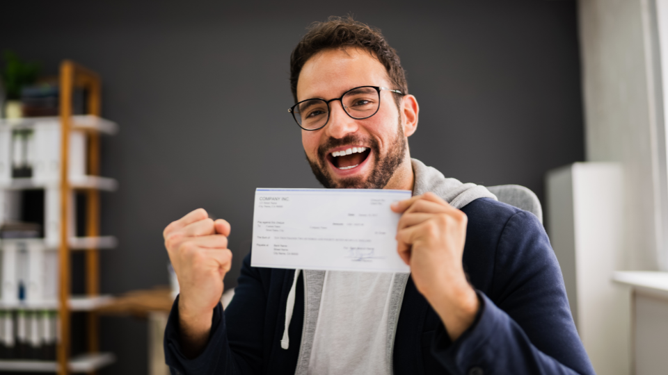 Happy employee showing off his paycheck